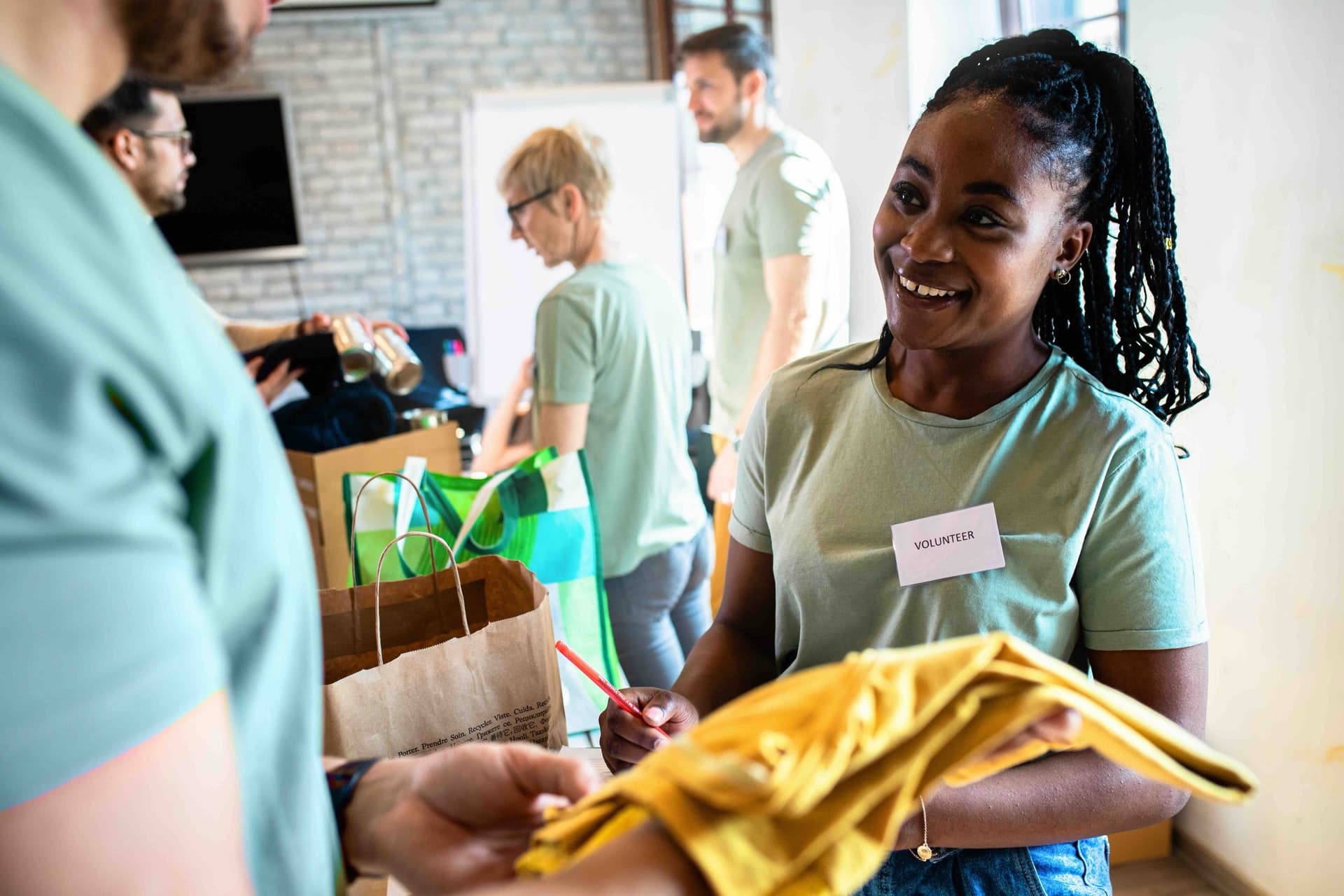 A smiling volunteer handing over donated goods